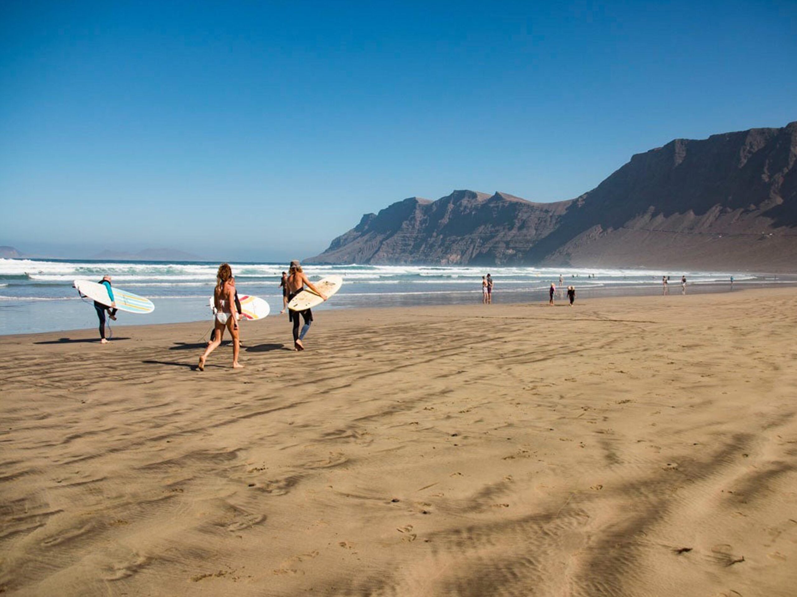 Group of people surfing on the beach in Lanzarote, Spain. Learn Spanish through adventurous activities like surfing.